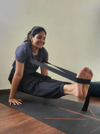 A smile of achievement while working on a challenging pose. This student uses a strap to assist in Brahmacharyasana, finding a balance between effort and ease, which is a core principle of our teaching.