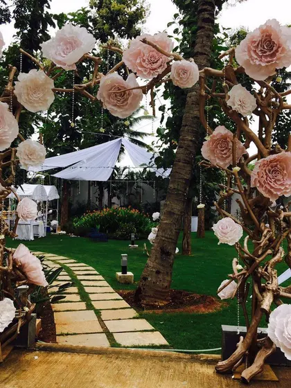 An enchanting garden entrance created with arches made of natural branches and adorned with large, soft-pink paper flowers. This sets a magical, bohemian tone right from the start.