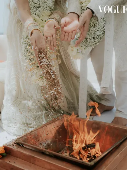 A close-up of a traditional ritual during the Mauritius wedding, featured in Vogue India. This shot focuses on the hands of the couple as they participate in the sacred fire ceremony, highlighting cultural details.