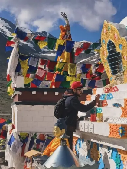 Another angle of me at work on the Stupa. The vibrant colors of the paint stand out against the white structure and the bright blue sky, surrounded by colorful Tibetan prayer flags.