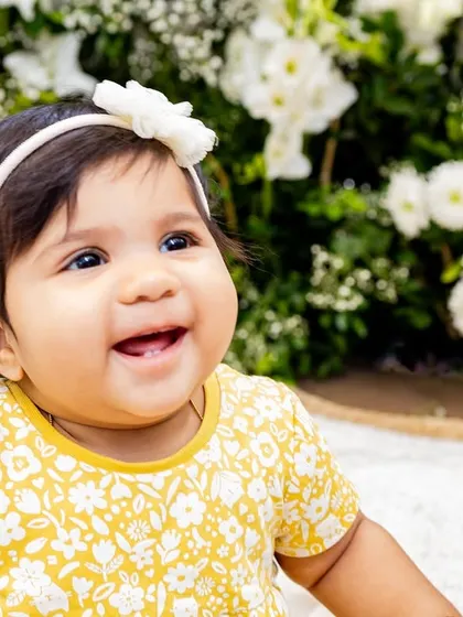 A happy baby girl in a field of flowers. The contrast in black and white makes this a striking and beautiful portrait.