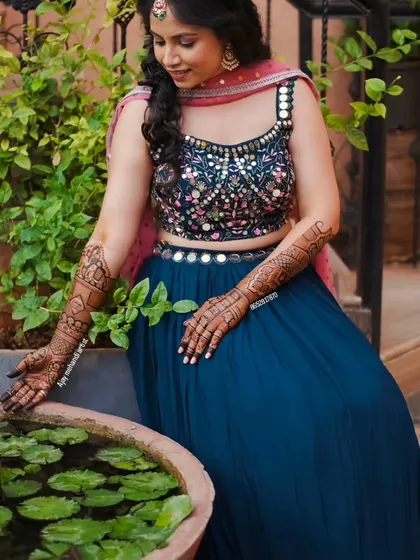 A beautiful shot of a bride by a lotus pond, her intricate mehndi complementing the serene and natural setting.
