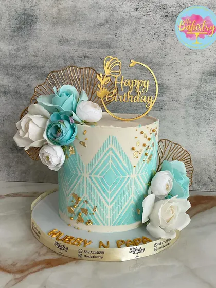 An elegant teal and white cake with a geometric pattern, gold leaf, and beautiful sugar flowers for "Hubby N Papa."