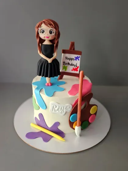 A cake for an artist. This design for Riya's birthday features an edible easel, paint palette, and a gorgeous figurine of the artist herself.
