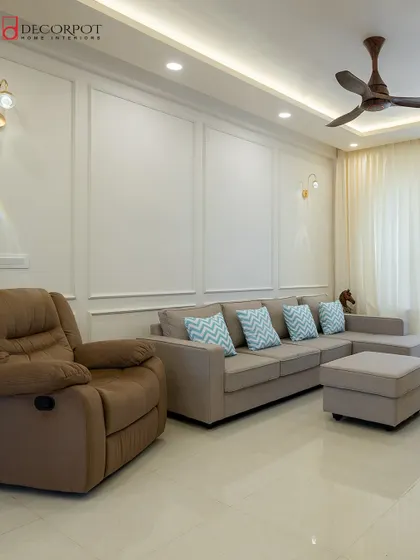 This comfortable living room features a sectional sofa with a recliner, perfect for movie nights. The simple wall moldings and warm lighting add a touch of classic elegance.
