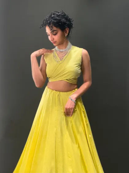 Dressed in sunshine and standing out effortlessly. This yellow lehenga isn't just an outfit, it's a statement, paired with a unique wrap-around blouse.