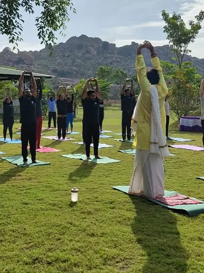 Our instructor leads a group in a standing stretch, with the beautiful rocky hills forming a stunning natural backdrop. Practicing with such a view is a truly inspiring experience.