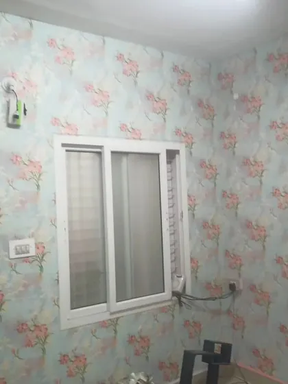 A bedroom with a soft blue wallpaper featuring a pink floral pattern, creating a delicate and romantic feel.