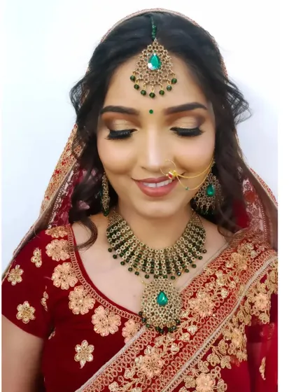 A smiling bride ready for her big day. This look features a flawless base, warm-toned eyeshadow, and beautiful green beaded jewelry.