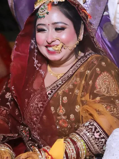 A candid, joyful moment during the wedding ceremony. The bride's smile lights up her face, showing off her radiant makeup.
