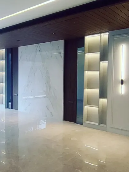 This image captures the moment when lighting and built-in features are installed. The backlit shelving and marble wall panel are in place, demonstrating how different materials come together.