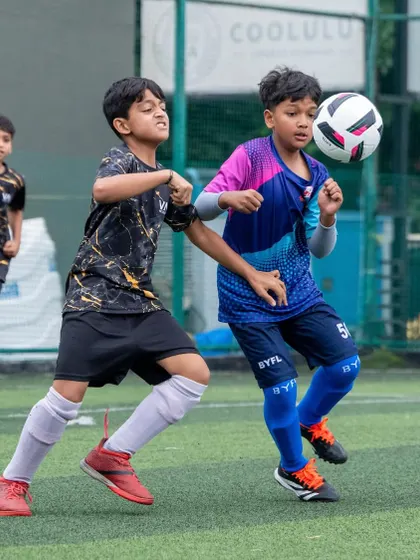 A U11 player showing great technique as he controls the ball with his chest during a competitive match.