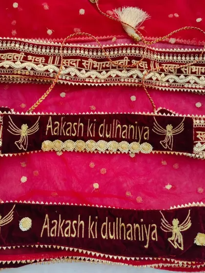 A personalized bridal accessory set, including a hanging velvet sign and a matching belt that says "Aakash ki dulhaniya".