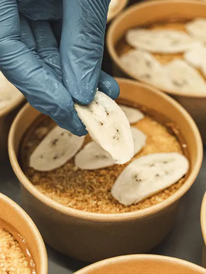 Fresh banana slices are carefully arranged over the biscuit base.