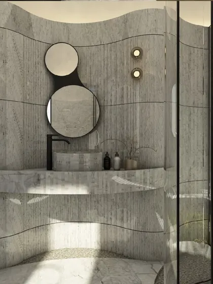 A detail of the curved marble bathroom, showing the custom vanity and the organically shaped double mirrors. The design uses flowing lines and natural materials to create a serene and immersive ambiance.