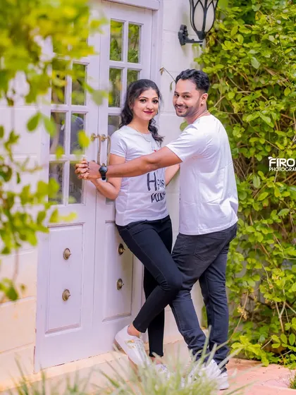 A playful, dancing pose in front of a white door. The couple's matching t-shirts and their fun interaction make this a very sweet and candid shot.