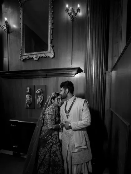 A timeless black and white portrait of the groom kissing his bride's forehead.