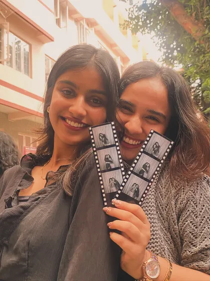 Two friends sharing a happy moment with their film-style photo strips at Cul Week.