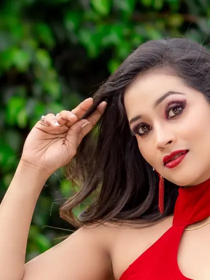 A close-up portrait of a model in a red gown, showing her glamorous makeup.