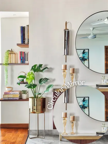 A large circular mirror makes a bold statement in this space. Paired with a brass planter and decorative wall sconces, it enhances light and adds a sense of glamour and depth.