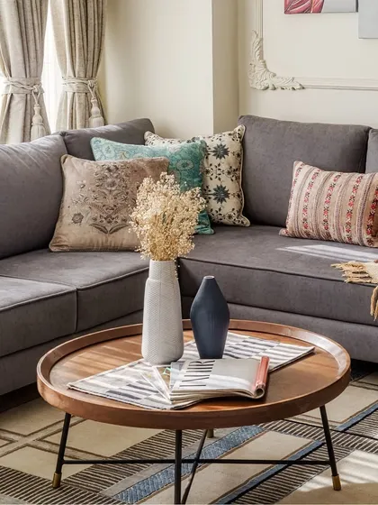A homey feel is achieved by layering textures and patterns. In this living room, a plush pink sofa, a geometric rug, and a gallery wall of plants by the window come together to create a lived-in, eclectic vibe.