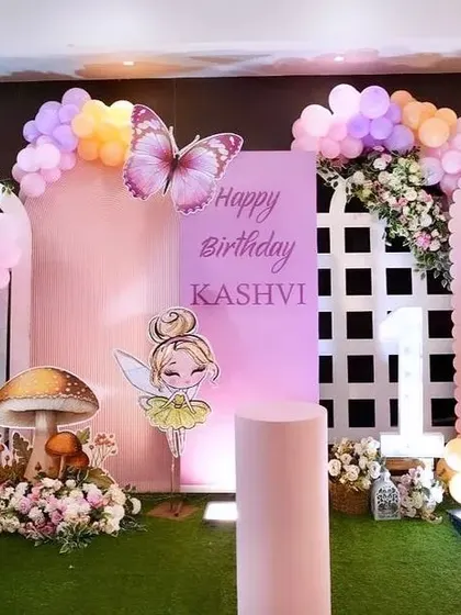 A whimsical fairy-themed birthday setup with pastel balloons, mushroom props, and floral arrangements.