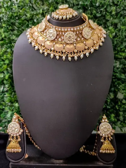 This classic temple coin necklace set, available for purchase, is perfect for creating an authentic South Indian bridal look. The set includes a choker, earrings, and a maang tikka.