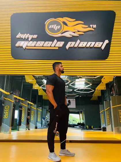 Standing proud in front of the Kitty's Muscle Planet logo. This gym is my second home and the heart of our fitness community.