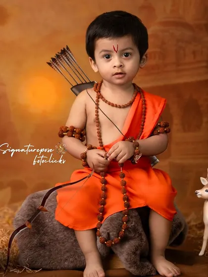 A meditative pose from a child dressed as Rama, holding his bow. The soft lighting and earthy tones of the set create a tranquil atmosphere, perfect for capturing the spiritual essence of the theme.