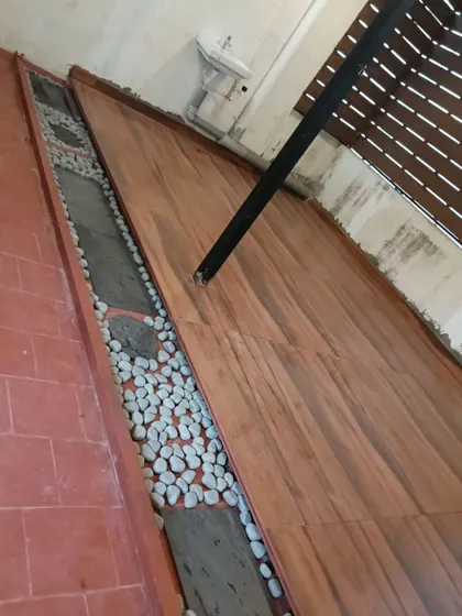An example of mixed-material flooring for a narrow side yard. We combined wood-look tiles for the main path with borders of terracotta tile and smooth river pebbles for a natural, textured look.