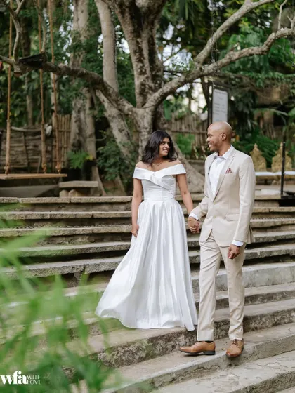 A couple in modern wedding attire walks down the stone steps, showcasing the venue's suitability for both traditional and contemporary celebrations.