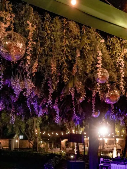 A magical Sangeet night ambiance created with hanging disco balls, cascading florals, and purple uplighting for a fun and glamorous party atmosphere.
