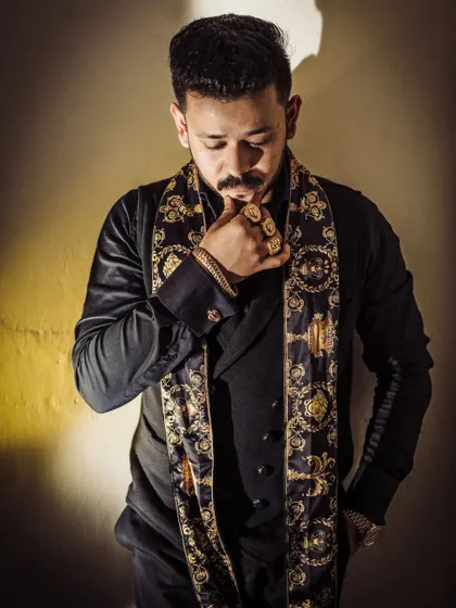 A dramatic male portrait using high-contrast lighting. The focus is on the thoughtful expression and the details of the luxury accessories, creating an image that is both stylish and introspective.