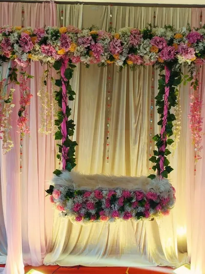The soft lighting highlights the delicate textures of the artificial flowers and drapes in this naming ceremony setup. It’s a testament to how beautiful artificial arrangements can be.