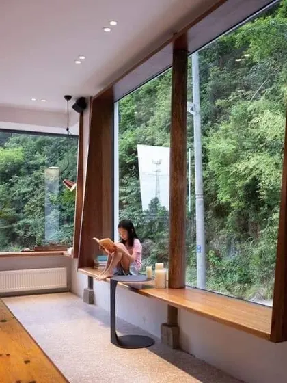 A simple yet beautiful window seat design. A long wooden bench along a large window provides a serene spot for reading and enjoying the view.