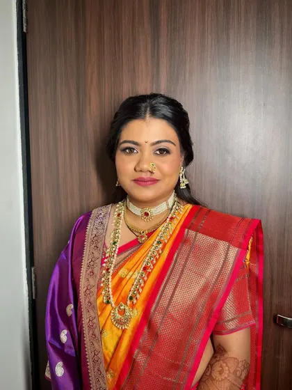 A Maharashtrian bridal look with a half-updo, adorned with fresh yellow flowers and a traditional ear chain. It's a beautiful blend of modern and traditional styles.
