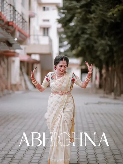 A joyful, dancing portrait of the bride in her elegant white and gold Kerala saree, full of life and happiness.