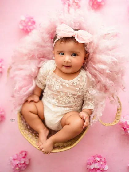 A sweet portrait of this baby girl sitting in a teacup, surrounded by pink fluff and flowers.