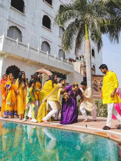 The whole family gets in on the fun! A playful moment as the bride is about to be pushed into the pool during her Haldi.