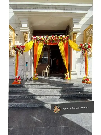 A classic and auspicious entrance decoration for a home event. Bright yellow and orange drapes are paired with fresh floral arrangements on top and on the sides, creating a beautiful archway for guests to walk through.