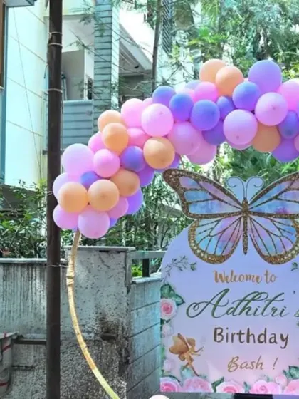 The welcome sign for a butterfly-themed birthday bash, featuring a circular arch of pastel balloons.