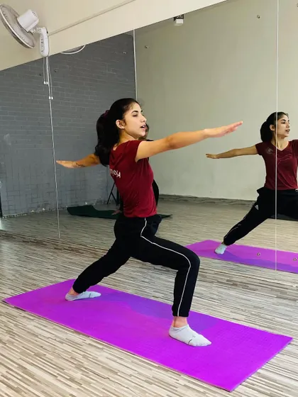 The Warrior II pose (Virabhadrasana II) is fundamental in yoga for building stamina and concentration. Here's a student holding the pose with strength and focus in front of the mirror, helping her check her alignment.