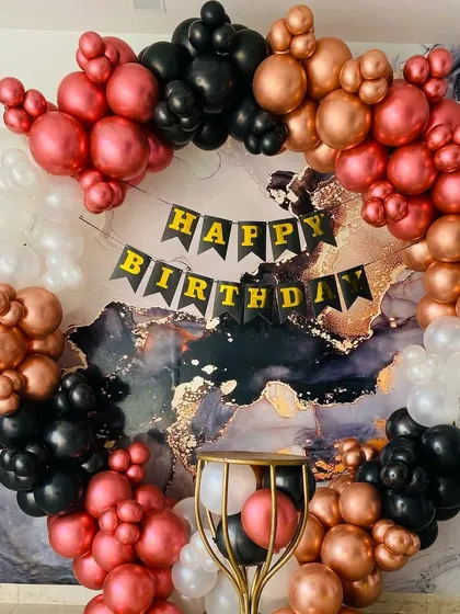 A bold and modern birthday backdrop featuring a balloon ring in black, white, and metallic pink against a marble-print background.
