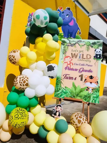 A 'Let's get wild' welcome sign for a jungle-themed first birthday. The sign is paired with a balloon arrangement featuring animal print and jungle-colored balloons.