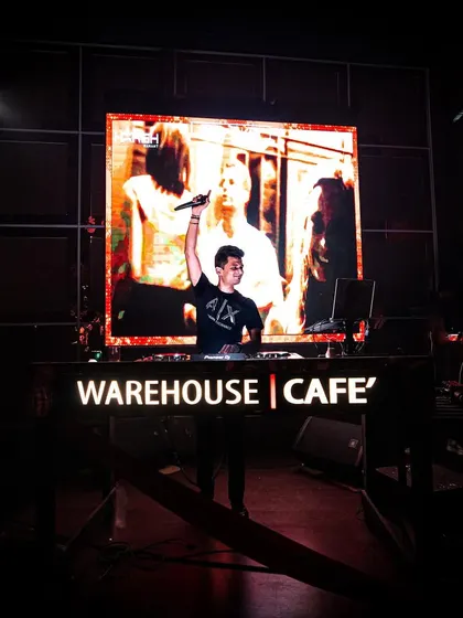 Taking the stage at Warehouse Cafe. My audio-visual setup allows me to project music videos and custom graphics, making the show a feast for the eyes and ears.