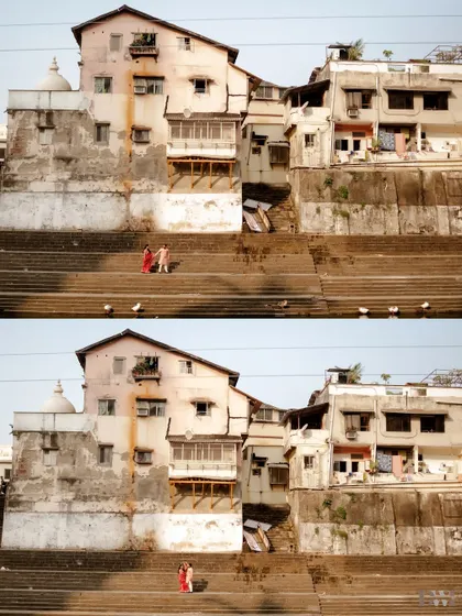 A wide shot showing the couple against the backdrop of old buildings by the ghat. This photo captures the scale and character of the location, placing their love story within a larger context.
