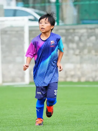 A young player running with intensity during a training drill.