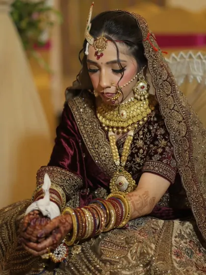 This bride looks serene and beautiful during her wedding rituals. Her makeup was designed to be timeless and elegant, complementing her velvet lehenga.