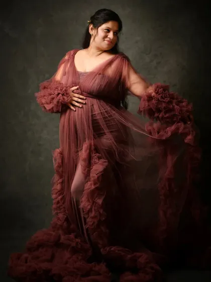 A playful and gentle portrait in a dusty rose tulle gown. The movement of the fabric adds a soft, ethereal quality to the image.