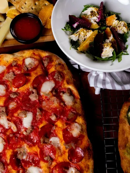 A beautiful spread for a catering event, featuring one of our meaty pizzas alongside fresh salads.